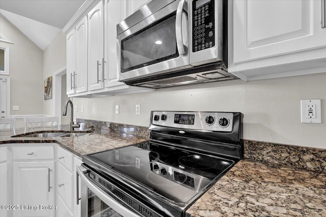 kitchen featuring lofted ceiling, sink, white cabinets, dark stone counters, and stainless steel appliances