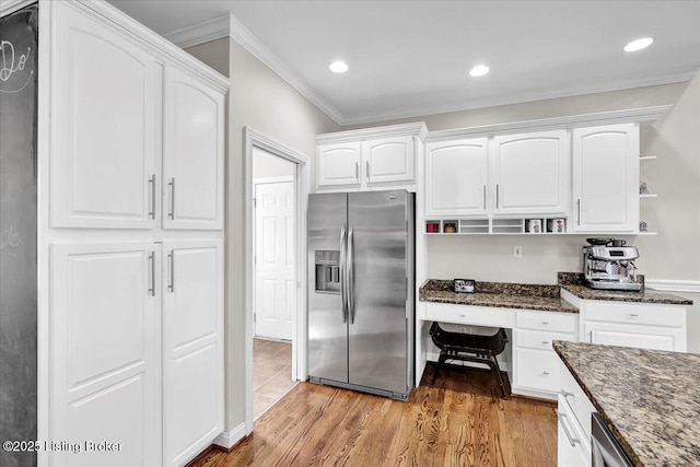 kitchen with white cabinetry, hardwood / wood-style floors, built in desk, stainless steel fridge with ice dispenser, and dark stone counters