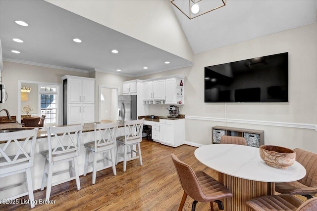 dining area featuring crown molding, vaulted ceiling, sink, and light wood-type flooring