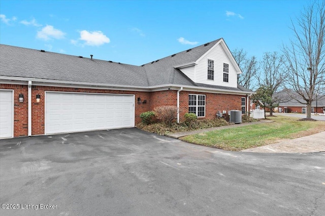 front facade featuring central AC, a garage, and a front yard