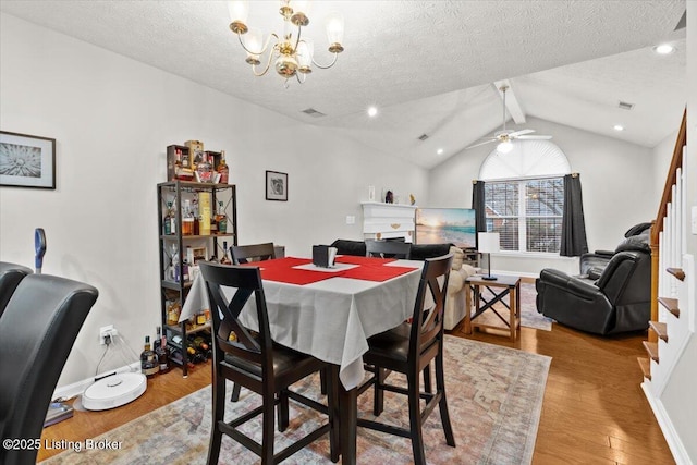 dining area with lofted ceiling with beams, ceiling fan with notable chandelier, a textured ceiling, and light hardwood / wood-style floors