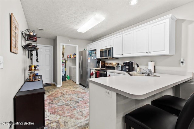 kitchen featuring gas water heater, a breakfast bar, white cabinetry, kitchen peninsula, and stainless steel appliances