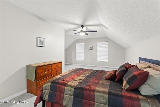 bedroom featuring vaulted ceiling, light colored carpet, ceiling fan, and a textured ceiling