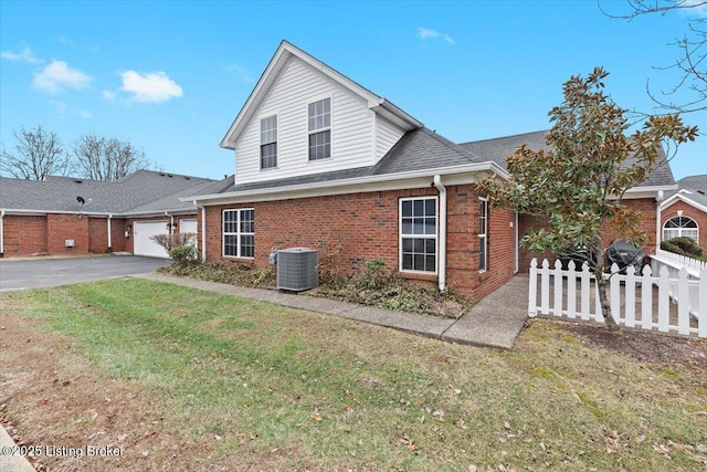 exterior space featuring a garage, a yard, and central AC unit