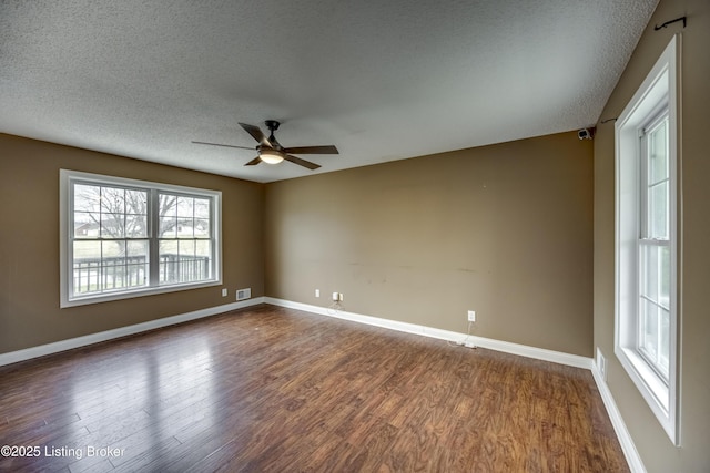 spare room with a textured ceiling, dark wood finished floors, a ceiling fan, and baseboards