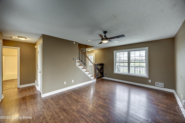 unfurnished room with stairway, wood finished floors, visible vents, and baseboards