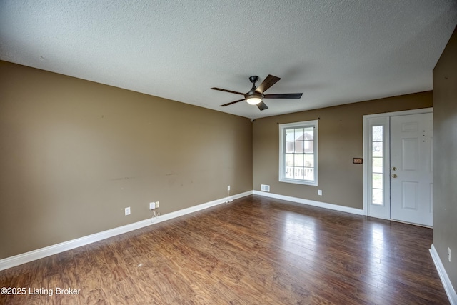 unfurnished room featuring visible vents, dark wood-type flooring, ceiling fan, a textured ceiling, and baseboards