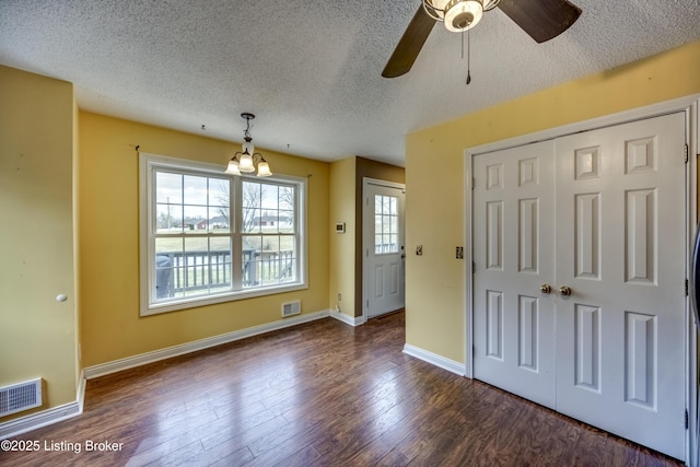 interior space with dark wood-type flooring, visible vents, a textured ceiling, and baseboards