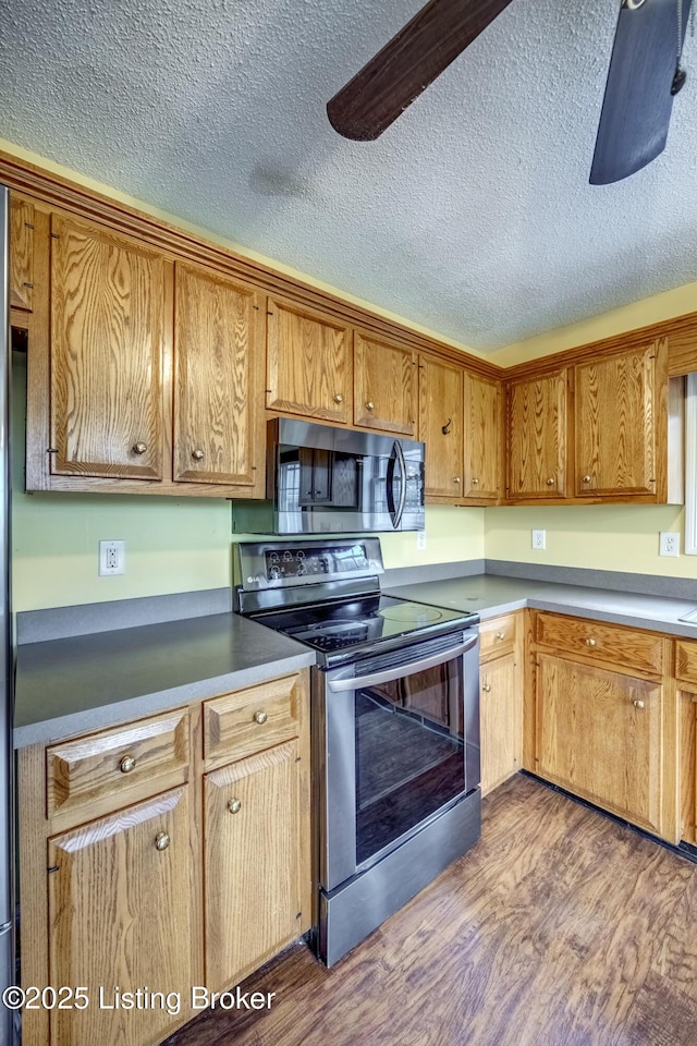 kitchen featuring ceiling fan, appliances with stainless steel finishes, and dark wood finished floors