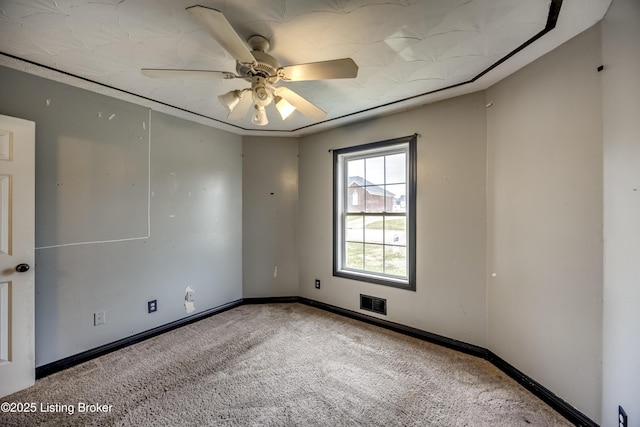 carpeted spare room featuring a ceiling fan, visible vents, and baseboards