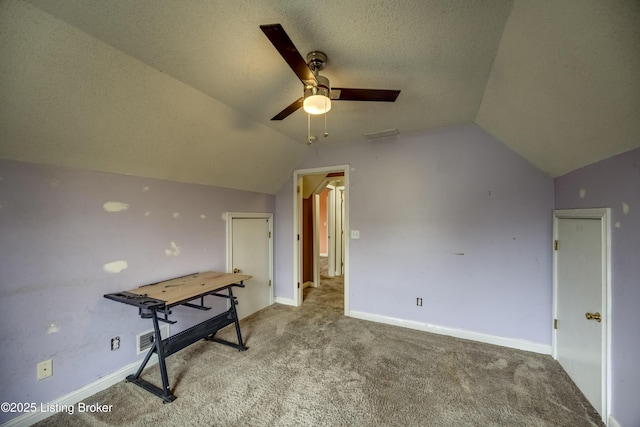 interior space featuring lofted ceiling, baseboards, a textured ceiling, and carpet