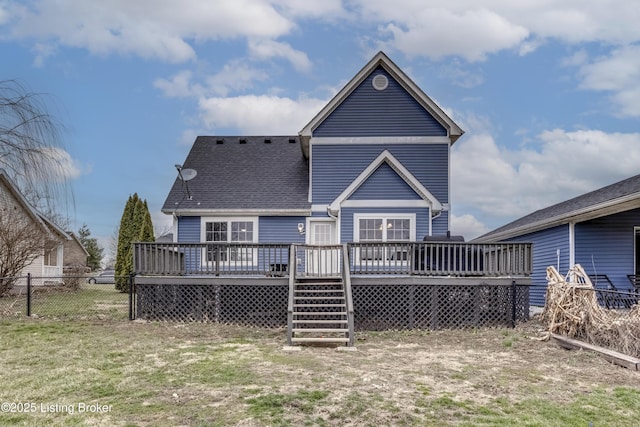 rear view of property featuring a shingled roof, fence, a wooden deck, and a lawn