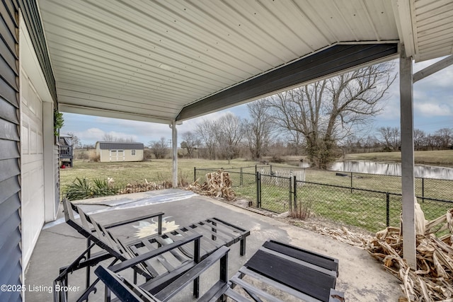 view of patio with a water view, fence, and an outdoor structure