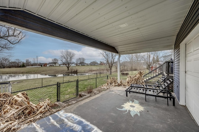 view of patio with a water view, fence, and a gate