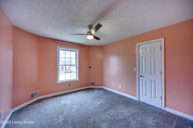 carpeted spare room with a ceiling fan, visible vents, a textured ceiling, and baseboards