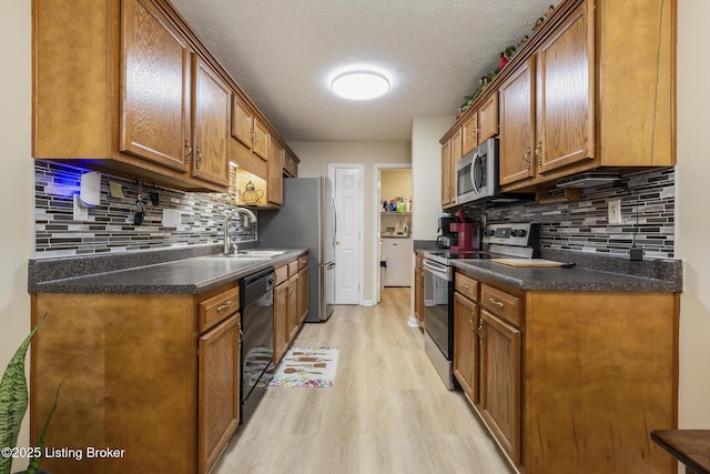 kitchen with sink, a textured ceiling, stainless steel appliances, light hardwood / wood-style floors, and backsplash