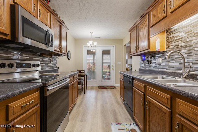 kitchen featuring appliances with stainless steel finishes, sink, hanging light fixtures, light hardwood / wood-style floors, and a textured ceiling