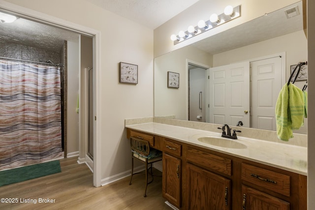 bathroom featuring vanity, wood-type flooring, a textured ceiling, and a shower with curtain