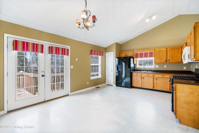 kitchen with sink, black fridge, range, decorative light fixtures, and vaulted ceiling