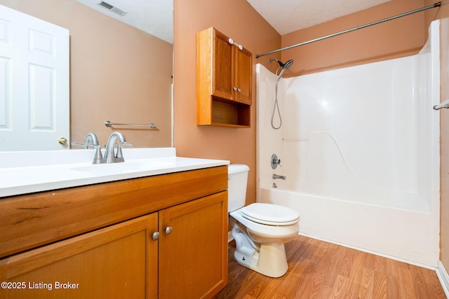 full bathroom featuring shower / tub combination, wood-type flooring, vanity, toilet, and a textured ceiling