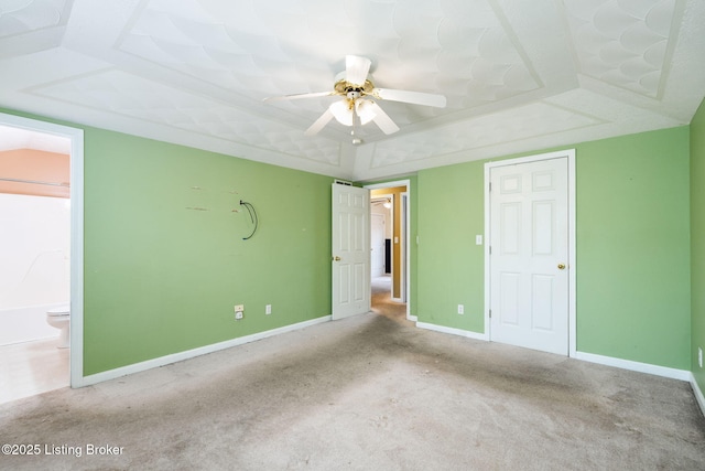 unfurnished bedroom featuring a raised ceiling, carpet, and ensuite bath