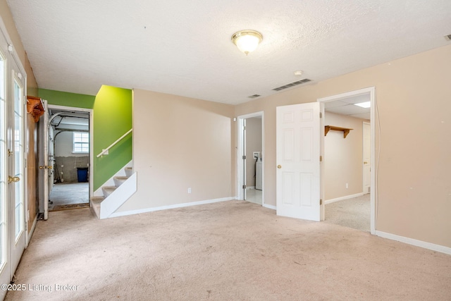 carpeted empty room featuring washer / dryer and a textured ceiling