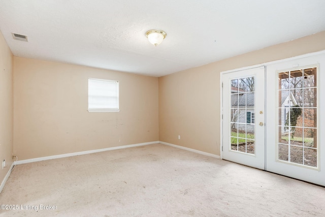 unfurnished room with carpet floors, french doors, and a textured ceiling