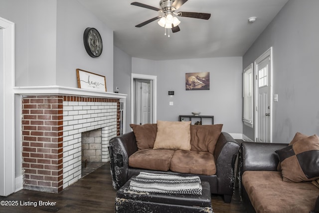 living room featuring dark wood-type flooring, ceiling fan, and a brick fireplace