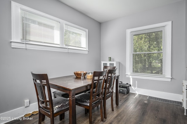 dining room with dark wood-type flooring and a healthy amount of sunlight