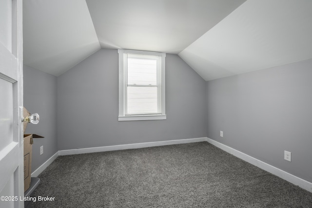 additional living space featuring dark colored carpet and vaulted ceiling