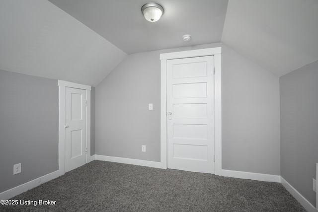 additional living space featuring vaulted ceiling and dark colored carpet