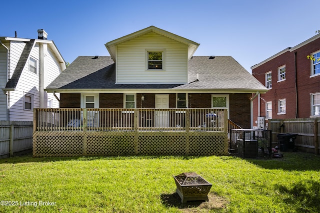 back of house with a wooden deck, an outdoor fire pit, and a yard