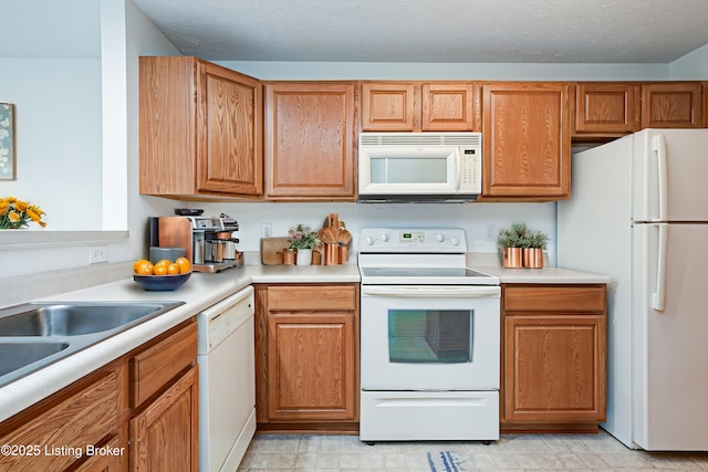 kitchen featuring sink, white appliances, and a textured ceiling