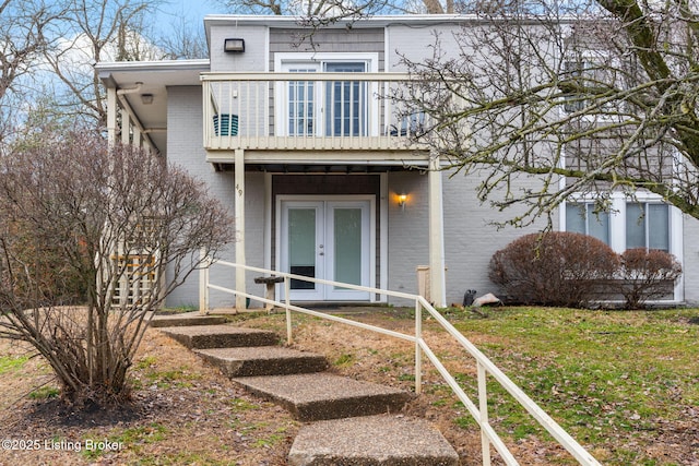 view of front of house with french doors, a balcony, and a front lawn