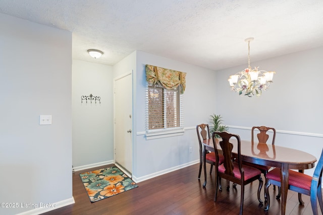 dining space featuring dark wood-type flooring, a chandelier, and a textured ceiling