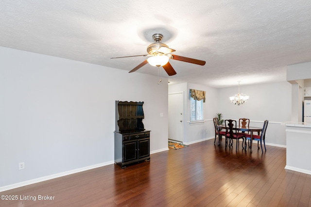 dining area with dark hardwood / wood-style floors, ceiling fan with notable chandelier, and a textured ceiling