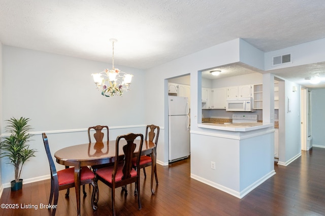 dining room featuring dark wood-type flooring, a textured ceiling, and a notable chandelier