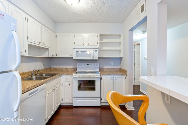 kitchen featuring dark wood-type flooring, sink, white cabinetry, a textured ceiling, and white appliances