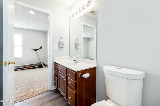 bathroom with hardwood / wood-style flooring, toilet, and vanity