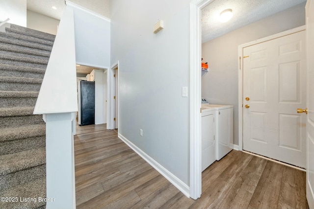 corridor with hardwood / wood-style flooring, a textured ceiling, and washing machine and clothes dryer