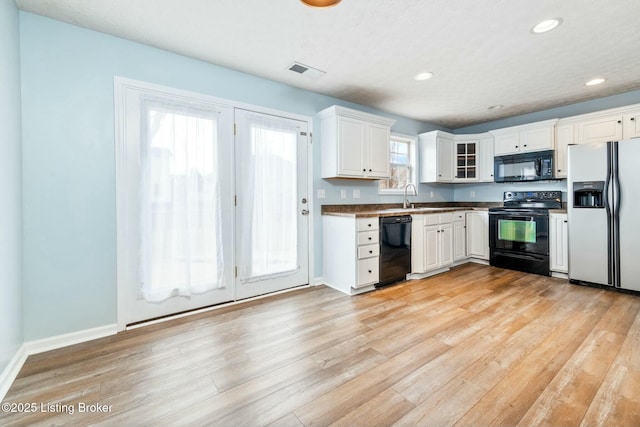 kitchen with light wood-type flooring, white cabinetry, and black appliances