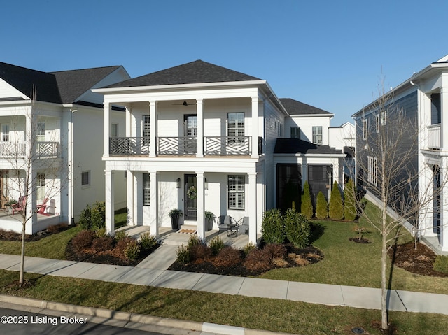 view of front of property featuring a balcony, covered porch, and a front lawn