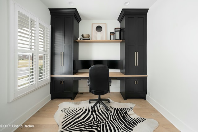 office space with built in desk and light wood-type flooring