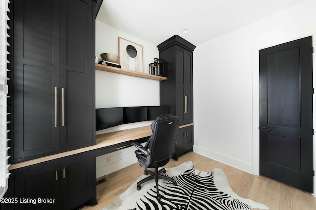 office space featuring built in desk and light hardwood / wood-style floors