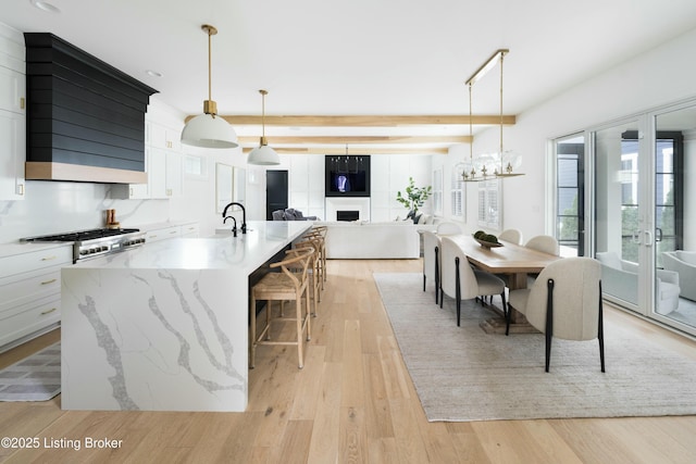 kitchen featuring a spacious island, white cabinetry, light hardwood / wood-style flooring, and decorative light fixtures