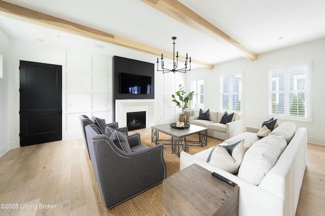 living room with an inviting chandelier, light hardwood / wood-style floors, and beamed ceiling