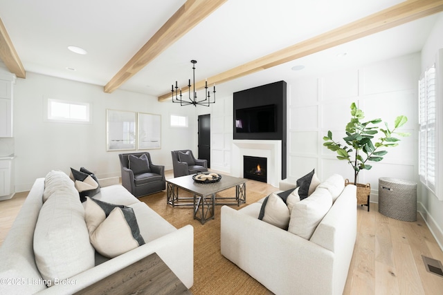 living room with beam ceiling, a chandelier, and light wood-type flooring