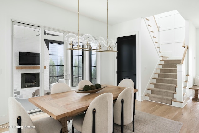 dining room featuring a brick fireplace and light wood-type flooring