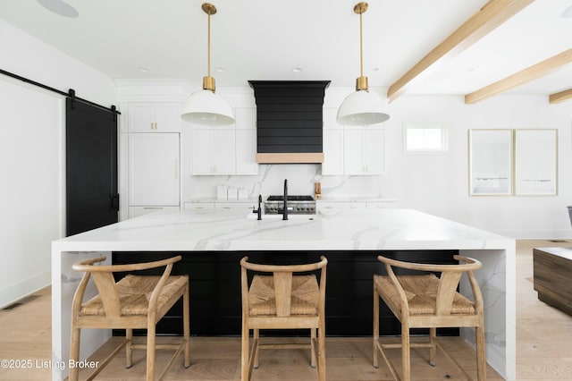 kitchen with light stone counters, a barn door, and decorative light fixtures