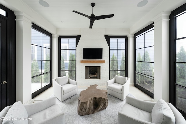 living room featuring a brick fireplace, ceiling fan, and ornate columns